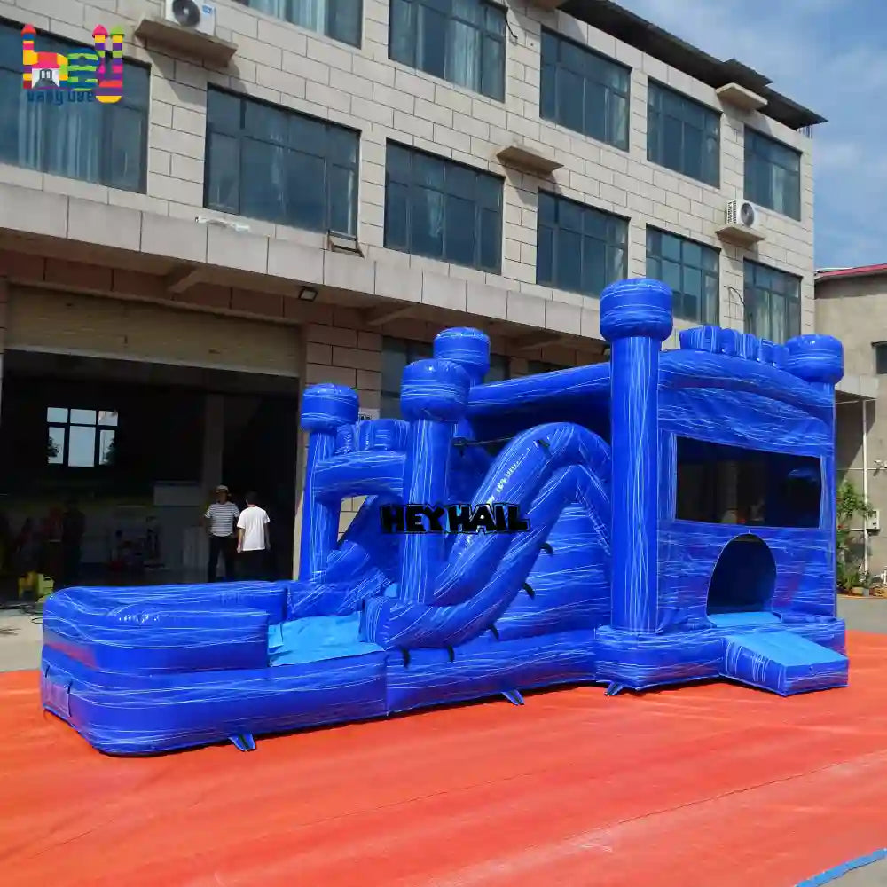 Outdoor angled view of a marble-blue inflatable castle combo with a slide