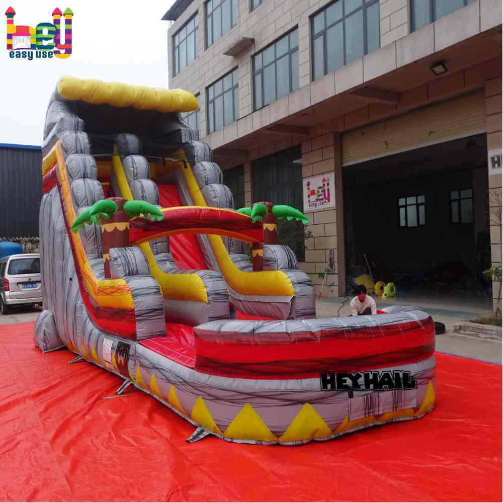Opposite angle view of red gray yellow single lane water slide with front pool and palm-tree accents