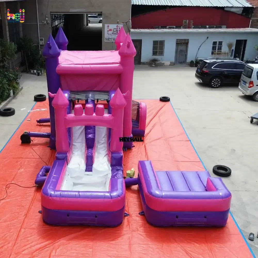Outdoor elevated view of a pink and purple inflatable castle wet dry combo with a slide and two rectangular landing pools