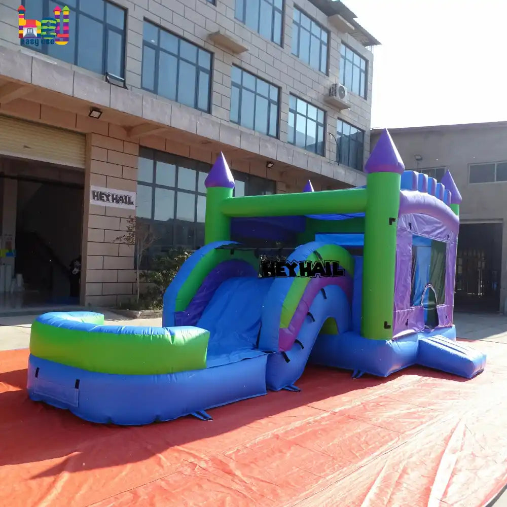 Outdoor close view of a purple, blue, and green inflatable castle combo with a slide