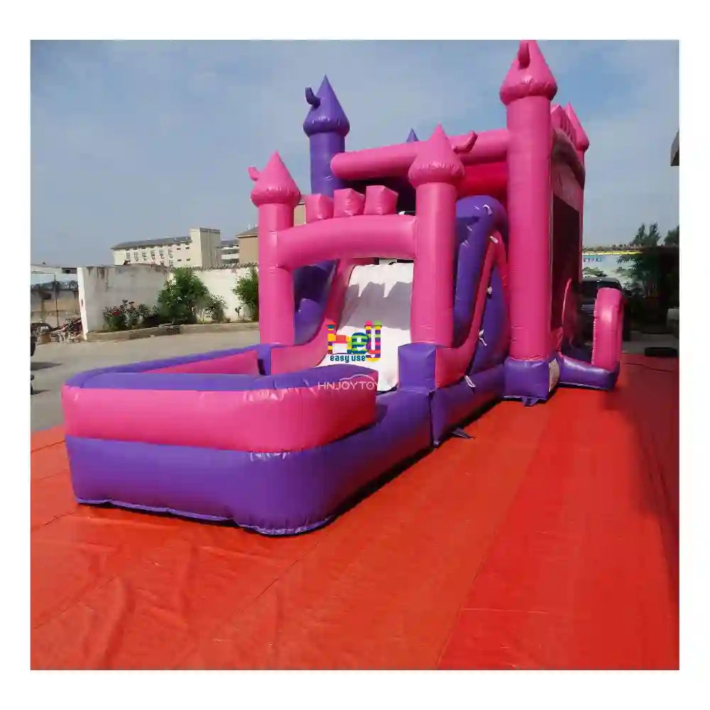 Angled outdoor view of a purple-and-pink wet dry inflatable combo with castle towers, slide, and attached landing pool