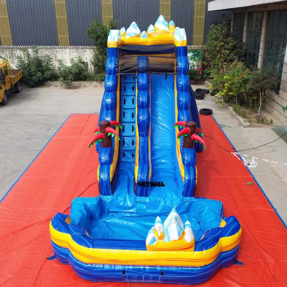 Front view of blue and yellow mountain water slide with climbing lane and splash pool