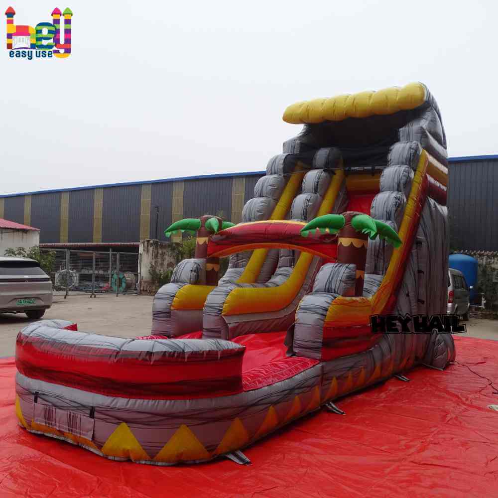 Angled view of red gray yellow single lane water slide with front pool and palm-tree accents