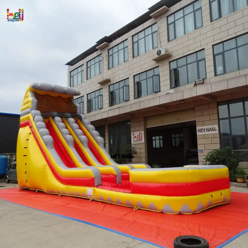 Angled outdoor view of a yellow-and-gray 22ft dual-lane inflatable water slide with a long rectangular landing pool