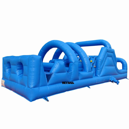 Studio side view of blue 30ft inflatable obstacle course with triple arch tunnels, crawl-through openings, climbing wall, and slide