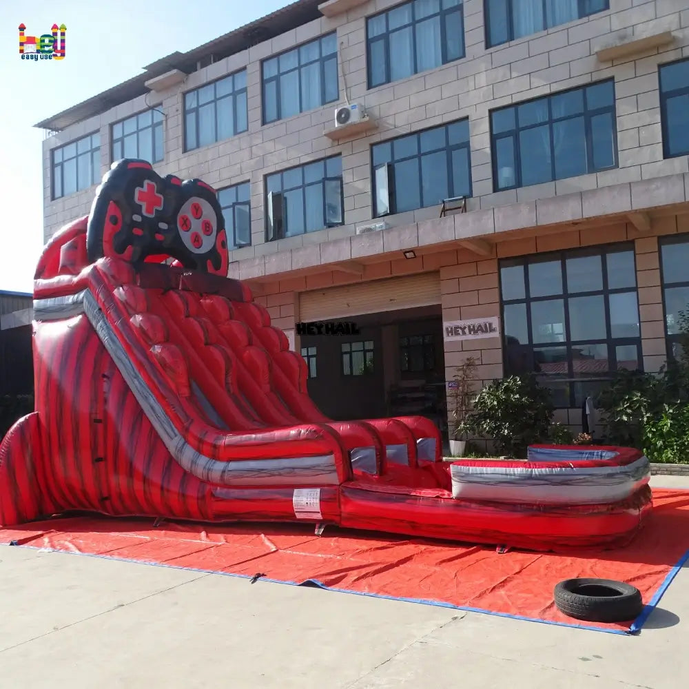 Outdoor angled front view of a red and gray 20ft dual-lane inflatable water slide with a game-controller arch and landing pool