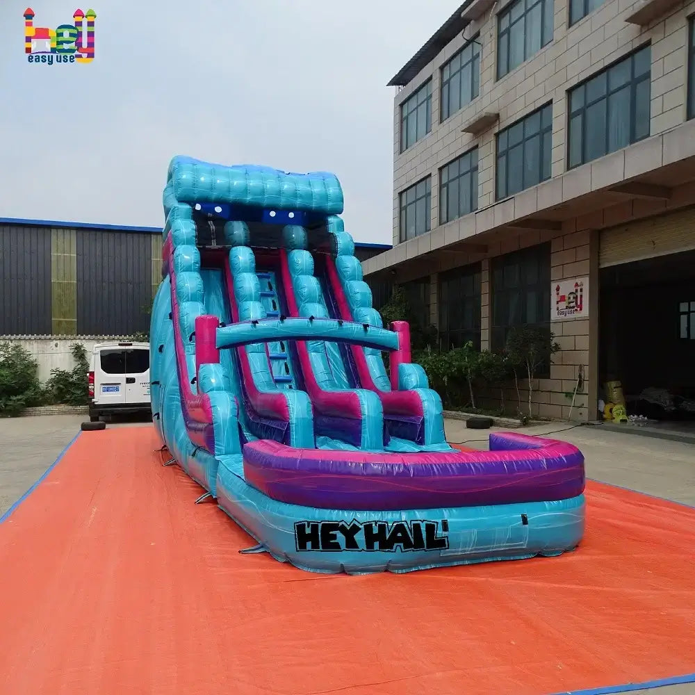 Outdoor front view of a blue-and-purple 18ft dual-lane inflatable water slide with a landing pool