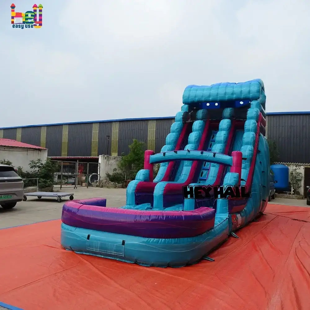 Outdoor angled front view of a blue-and-purple 18ft dual-lane inflatable water slide with a landing pool