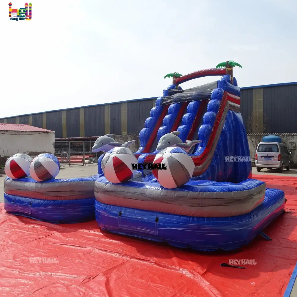 Outdoor angled front view of a marble-blue dual-lane inflatable water slide with dolphin accents and beach balls