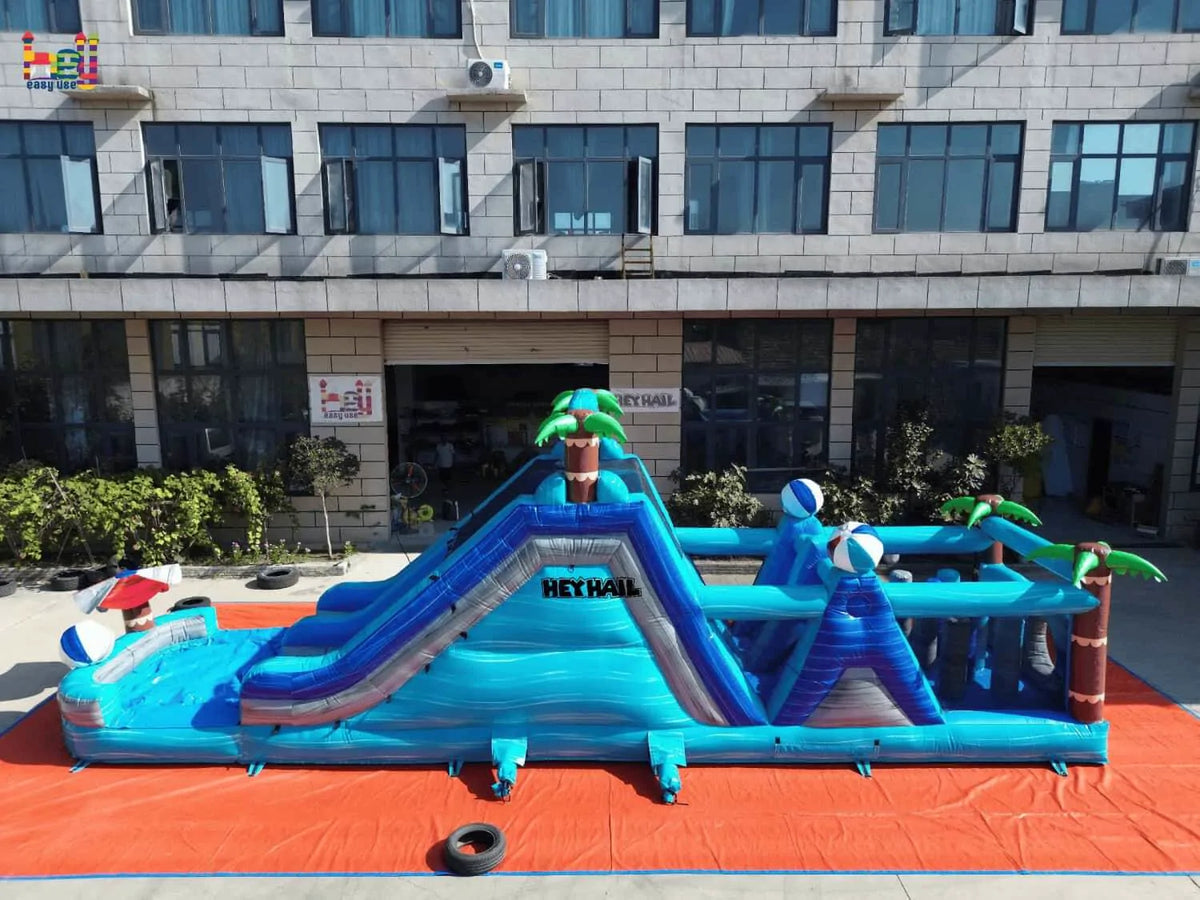 Side view of the tropical dual-lane inflatable obstacle course with a slide