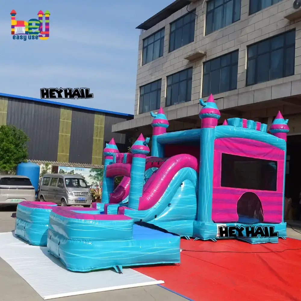 Outdoor angled view of a blue-and-pink inflatable castle combo with a slide
